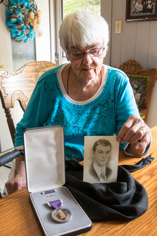 Fran Nutter displays her older brother Bernard's picture and his Purple Heart. 